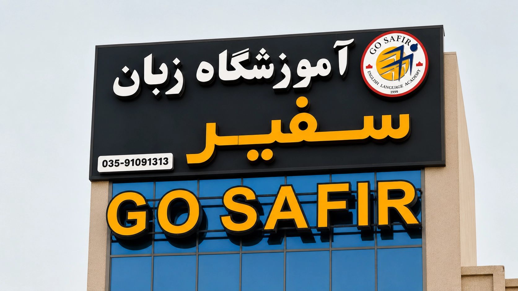 تابلوی چلنیوم و نورانی آکادمی سفیر با نوشته "آموزشگاه زبان سفیر" و عبارت "GO SAFIR" بر روی نمای شیشه‌ای ساختمان در هنگام غروب.